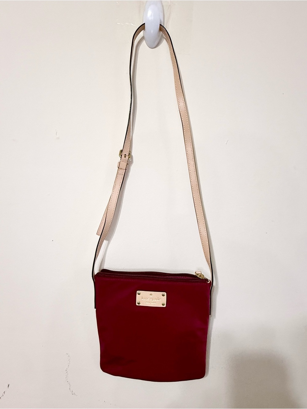 kate spade burgundy crossbody with beige strap and gold plaque